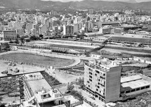 Joan Riera Un canódromo, un velódromo y una pista de atletismo. Tres formas ovaladas destinadas a la competición reunidas en la curiosa fotografía de Torrelló. Esta triple coincidencia debe ser tan improbable como que te toque la lotería, sin embargo, estaba en sa Riera. El primero en llegar, allá por 1909, fue el velódromo de Tirador. El nombre le viene de que allí, en las afueras de las murallas, era donde los cordeleros estiraban las sogas. Lo construyó el Veloz Sport Balear y fue escenario de gloriosas carreras de ciclismo, pero también de combates de boxeo o lucha libre y de los primeros partidos de fútbol disputados en Palma. En 1973 dejaron de rodar las bicicletas y tuvo destinos menos gloriosos, como pistas de squash o depósito de coches del Ayuntamiento. La fiebre por los canódromos llegó a España en los años 20. El de Palma, junto con los de Madrid y Valencia, fue de los primeros. Era territorio de los gentleman, de hecho fueron los nobles quienes los importaron. En los años 60, el ambiente era radicalmente distinto. Los dueños de los galgos los paseaban por la calle de Jesús, que se convertía en un territorio peligroso para los zapatos de los paseantes. En el interior del recinto, los apostantes en las carreras se mezclaban con los alumnos de La Salle o del Instituto que habían hecho fullet. Hoy resulta difícil distinguir la pista, que ha sido invadida por los hierbajos. En el Club MIlitar es Fortí se construyó el tercer óvalo: la pista de atletismo. Este era territorio vedado para la mayoría de los ciudadanos. Solo tenían acceso los miembros del Ejército, sus familias y algunos amigos. Los alumnos de La Salle practicábamos el atletismo sobre la pista de ceniza. Cien lisos, mil, salto de longitud... pruebas en las que no se batió ningún récord del mundo pese a los esfuerzos del profesor Gelabert, a quien todos llamábamos el Káiser, quizás por su imponente figura, su pelo cano y su vozarrón grave. Tres óvalos estirados, una pista para que compitan los perros, otra para las bicicletas y la tercera para los humanos. ¡Ah! Y al fondo el hoy también abandonado Lluís Sitjar.